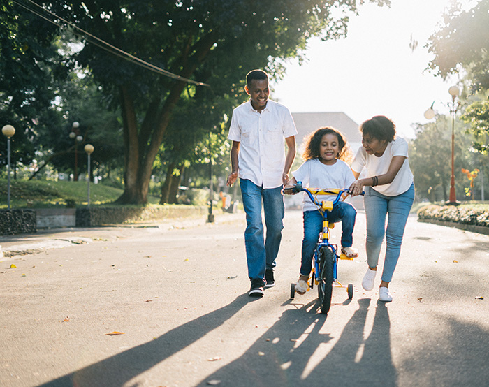 Parents assisting child ride a bike